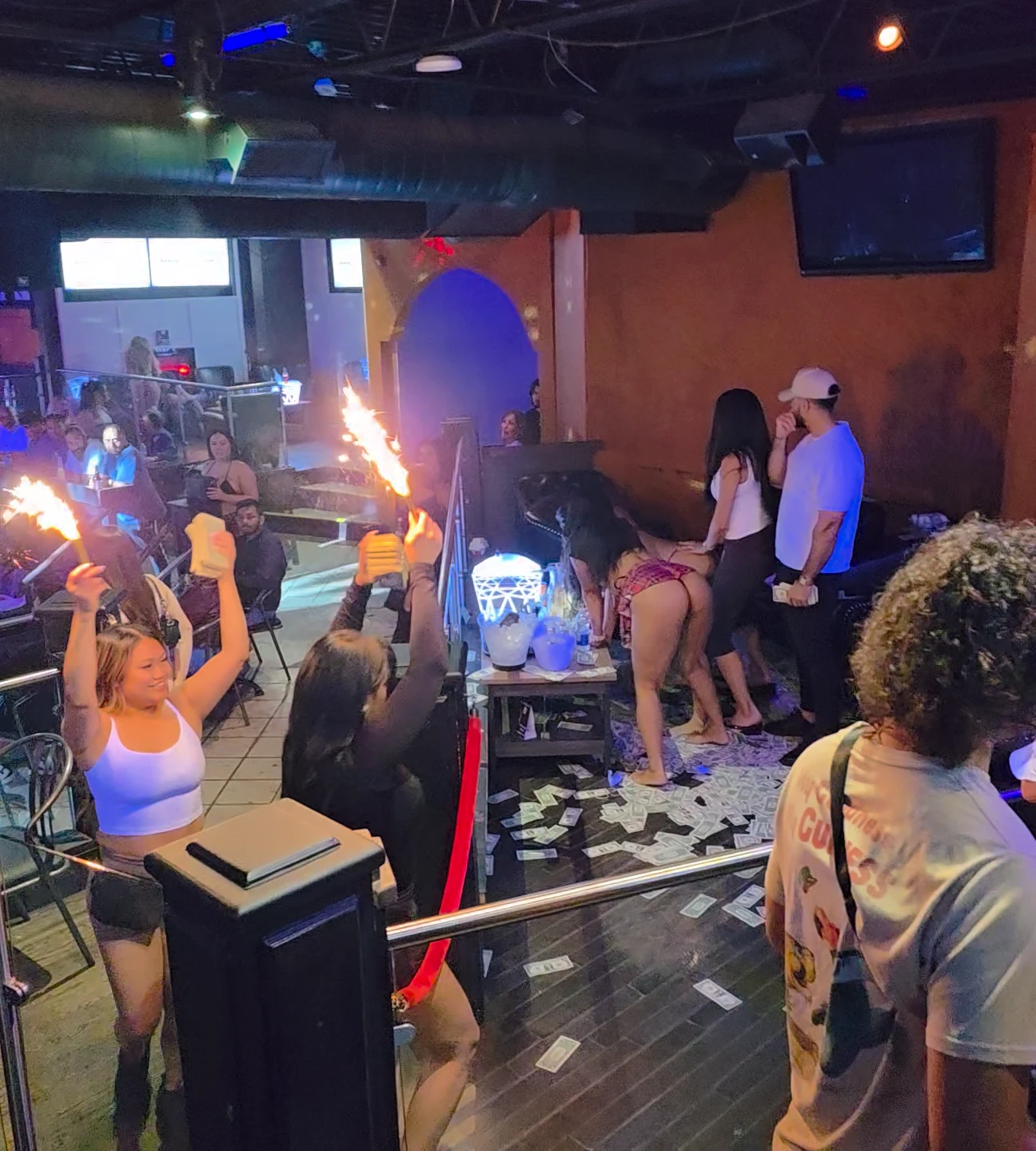 Whiskey bottle-service staff raise sparklers as they arrive at a guest booth.
