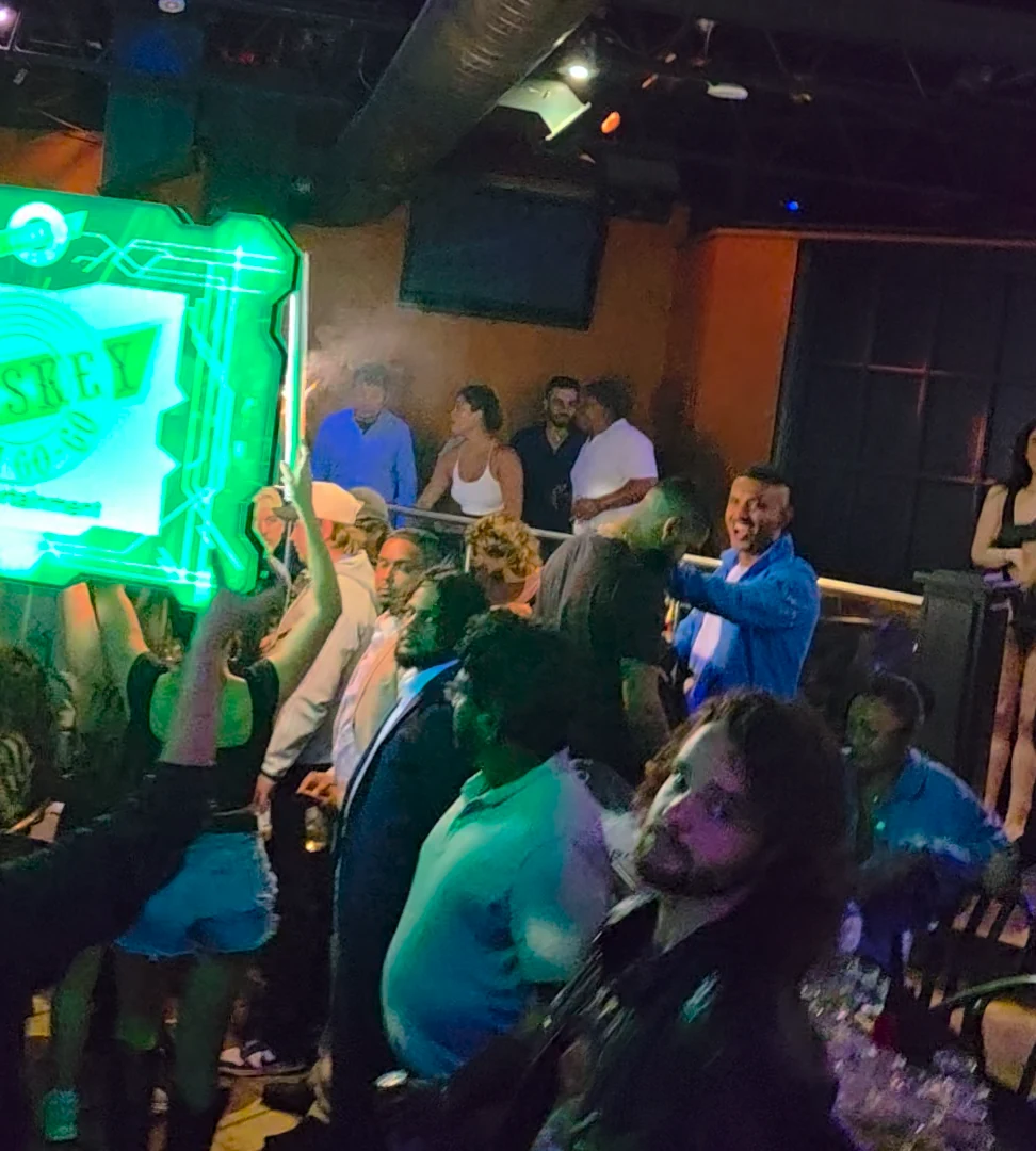 Guests cheer as bottle service and an illuminated Whiskey sign arrive at their booth.