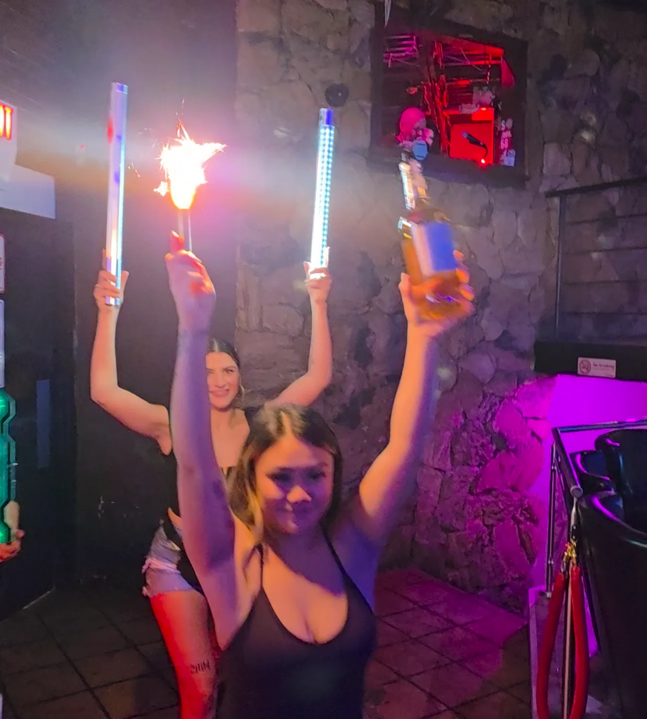 Whiskey bottle-service staff carrying illuminated bottles and sparklers into the room.