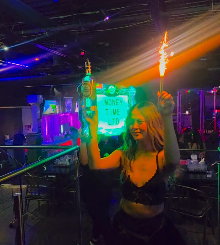 A sparkler bottle-service arrival in golden and purple club lighting