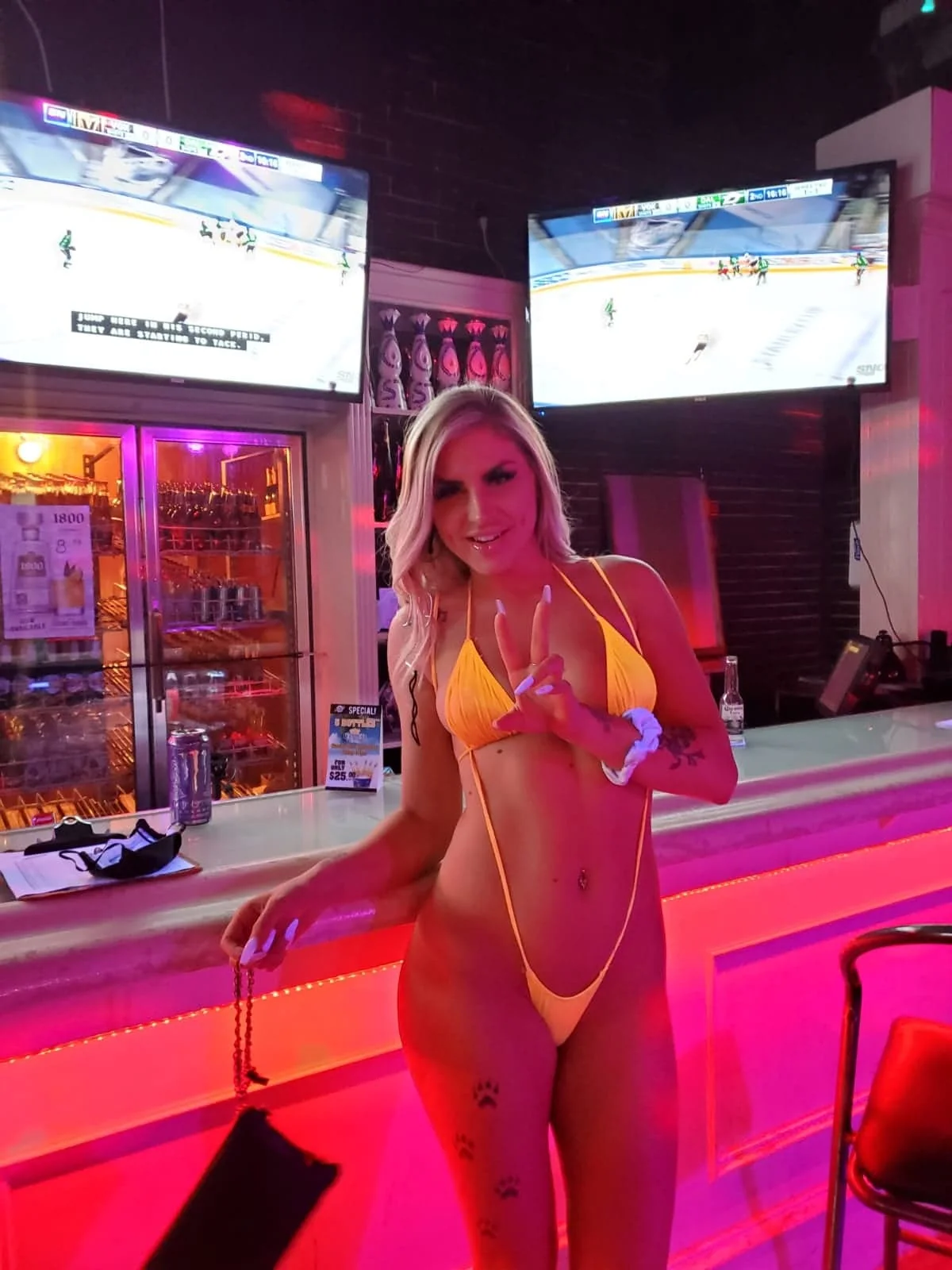 Performer in pink stage attire beside the illuminated bar.