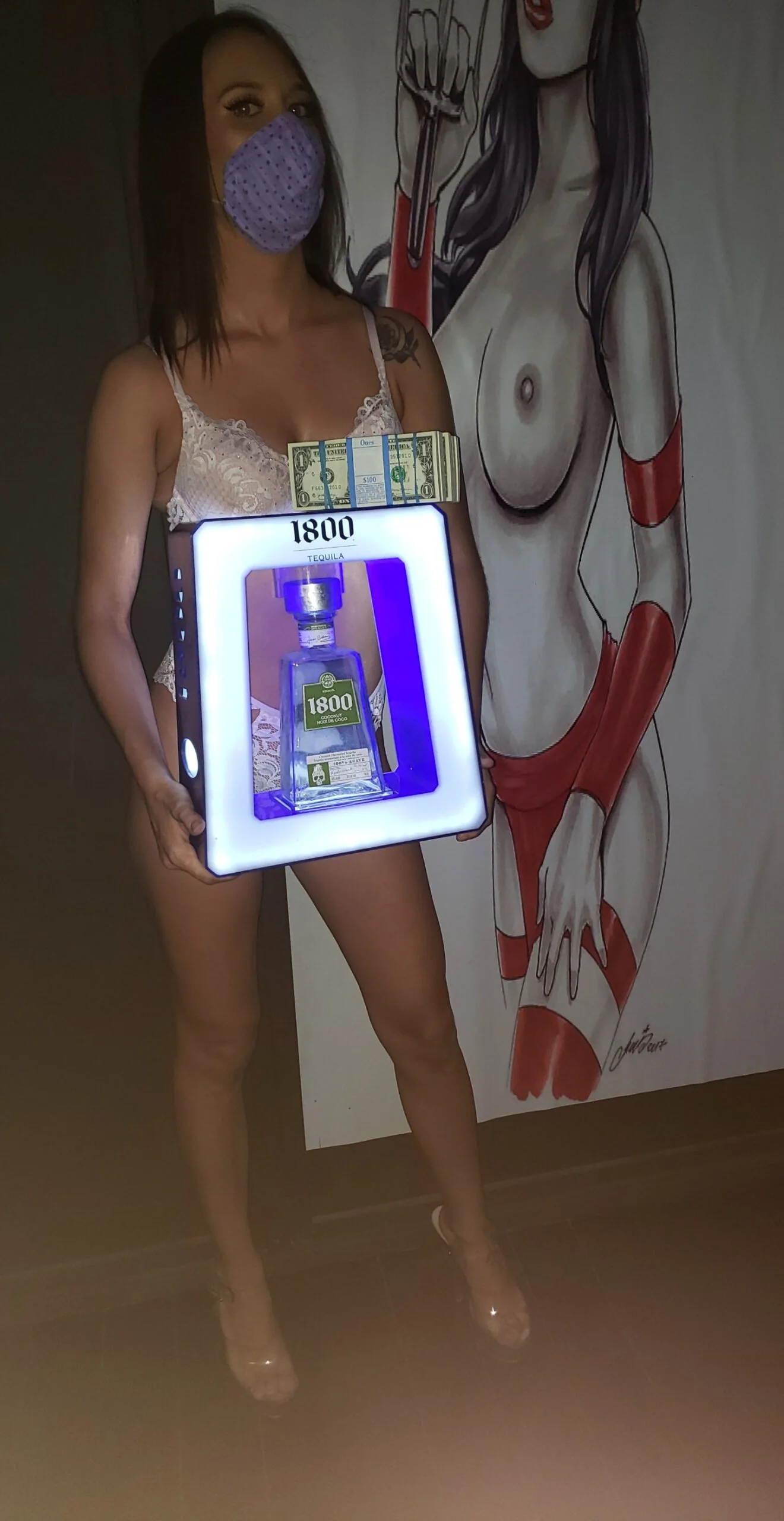 Performer presenting a bottle-service display beside venue artwork.